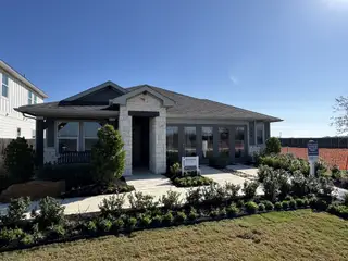 Street view A beautiful stone-accented home with lush landscaping in Waterstone Crossing by Meritage Homes (Kyle, TX).