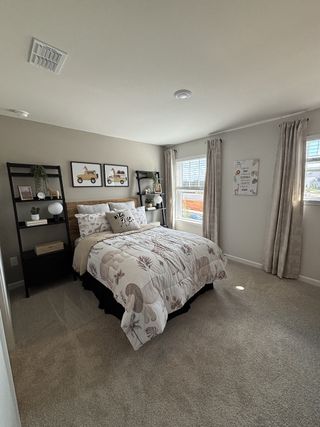 A cozy bedroom featuring a patterned comforter, natural light, and modern shelving.