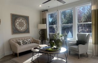 Model Home A cozy living room with elegant seating, a round coffee table, and large windows inviting natural light.