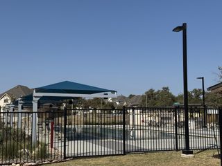 Community Amenities A private community pool with shaded seating, offering a relaxing escape in Bluffview by Taylor Morrison (Leander, TX).