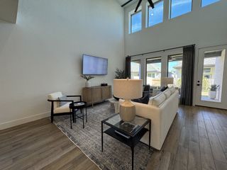 An elegant living room with high ceilings, large windows, and sleek furnishings in a modern, airy space.