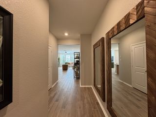 A modern hallway with wood flooring and decorative mirrors leading to a spacious living area.