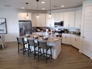 A modern kitchen featuring sleek white cabinetry, stainless steel appliances, and pendant lighting over a spacious island.