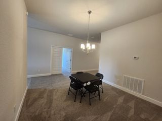 A cozy dining room with plush carpet, elegant chandelier lighting, and folding table and chairs for an intimate setting.