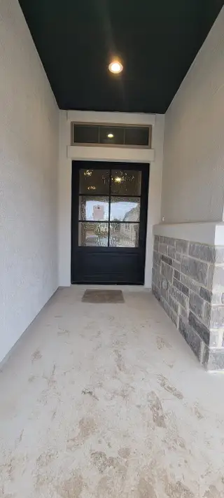 A welcoming entryway with a stone accent wall, modern door, and warm lighting.