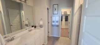 A stylish master bathroom featuring dual sinks, a large mirror, and direct access to a spacious walk-in closet for ultimate convenience.