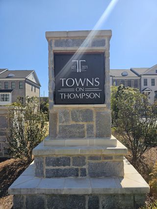 A welcoming entrance sign for Towns on Thompson by The Providence Group in Alpharetta, GA, framed by elegant townhomes.