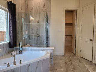 Luxurious bathroom with marble-tiled floors, a spacious corner tub, and elegant glass shower enclosure.