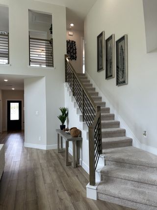 A modern hallway showcasing a wooden staircase with sleek railings, framed art, and stylish decor.
