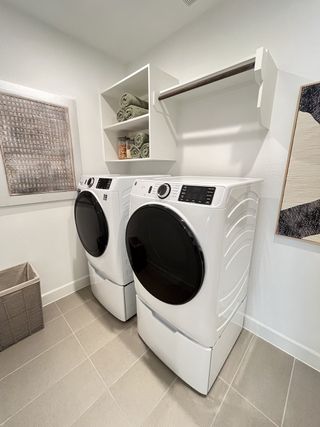 A sleek laundry room featuring modern appliances, open shelving, and stylish decor accents.