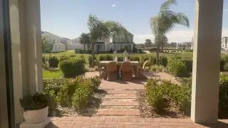 A charming patio with palm trees, a dining set, and lush landscaping.
