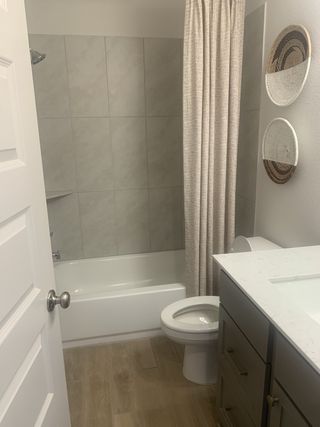Model Home A cozy bathroom featuring a tiled shower, sleek vanity, and earthy wall decor.