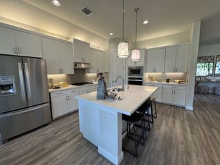 A modern kitchen with sleek white cabinets, stainless steel appliances, and an elegant island with pendant lighting.