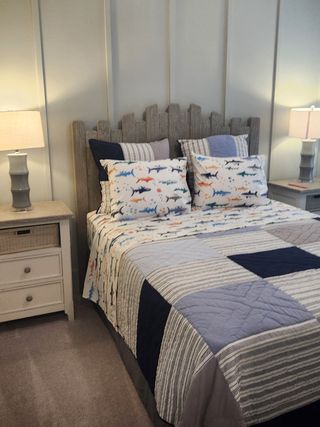 Model Home A cozy bedroom with a unique headboard, playful shark-themed bedding, and matching side tables with soft lighting.