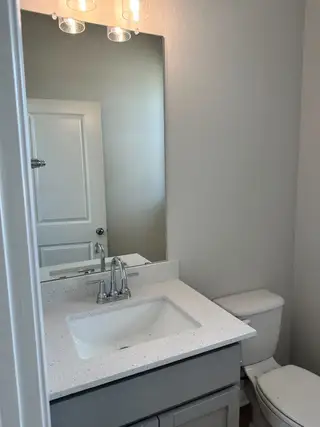 A modern bathroom featuring a sleek vanity, quartz countertop, large mirror, and contemporary lighting.