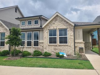 Street view A charming brick home with manicured landscaping in Lake Parc Village Townhomes by Veralux Homes (Fort Worth, TX).