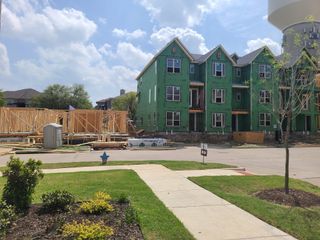 Street view New construction site with green-sheathed townhomes in Wade Settlement by Megatel Homes, Frisco, TX.