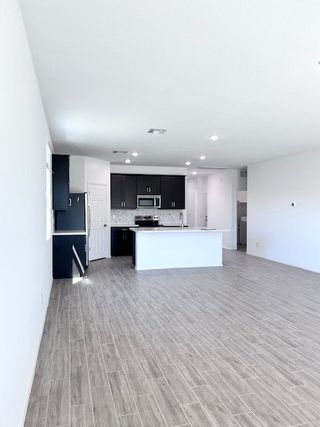A spacious kitchen with dark cabinets, sleek appliances, an island, and wood-look flooring. Bright and modern space.