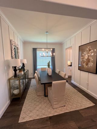 Model Home A modern dining room featuring an elegant chandelier, sleek table, and chic decor with a cozy, patterned rug.