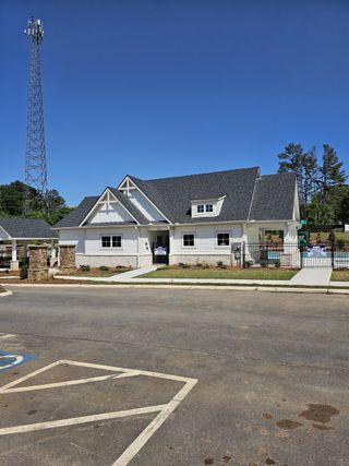 Community Amenities Charming white home with a dark roof in Diamante by DRB Homes, Stockbridge, GA. Features a landscaped entrance.