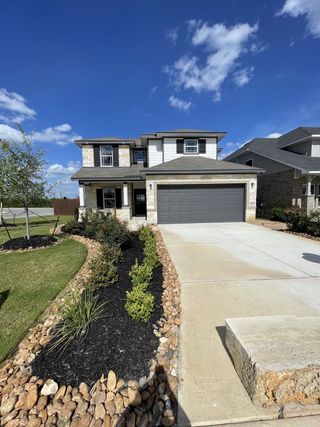A modern two-story home with stone accents and a landscaped yard in Hunters Ranch by First America Homes (San Antonio, TX).