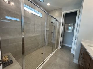 A sleek bathroom features a spacious glass-enclosed shower, neutral tile, and elegant fixtures for a modern touch.