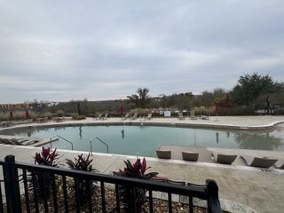 A serene community pool with loungers and lush landscape in Whisper Valley by GFO Home (Manor, TX).