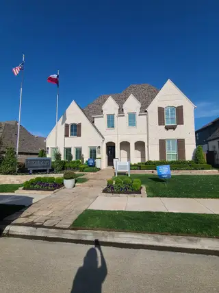 Street view A beautiful white brick home with manicured landscaping in Star Trail: 65ft. lots by Highland Homes (Prosper, TX).