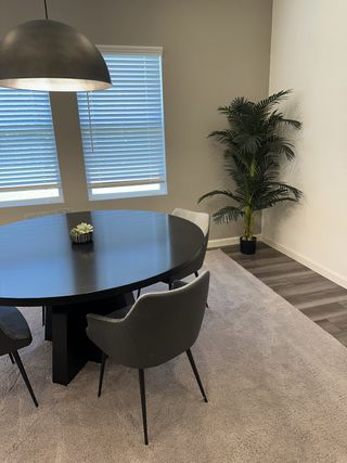 A modern dining room featuring a sleek round table, contemporary chairs, and a stylish pendant light.