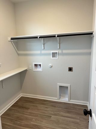 A functional laundry room with gray walls, wood-look flooring, and open shelving. Perfect for modern convenience.