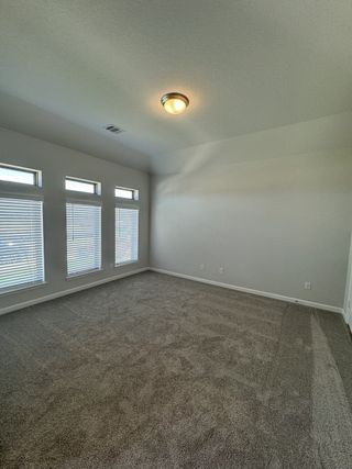 Model Home A spacious primary bedroom with tall ceilings, large windows, and plush carpeting, offering a bright and airy retreat.