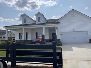 A charming white home with dormer windows and a landscaped yard in Sweetgrass at Summers Corner by Lennar (Summerville, SC).