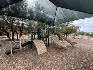 Community Amenities A well-equipped playground with slides and climbing structures sits under a large shade canopy in Lakeside at Lake Georgetown by Coventry Homes (Georgetown, TX).