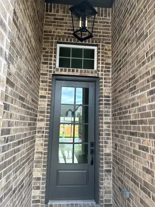 A dark paneled door set in a brick entryway, enhanced by a classic lantern fixture above.