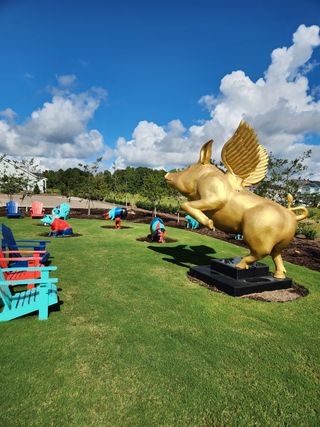 A vibrant park in Wendell Falls by Garman Homes, featuring a whimsical golden winged pig statue and colorful seating (Wendell, NC).
