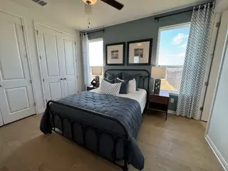 A cozy bedroom with a dark metal bedframe, soft blue bedding, and patterned curtains complementing the serene ambiance.