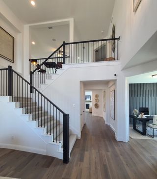 A modern interior featuring an elegant staircase, hardwood floors, and a bright, open hallway leading to a stylish office space.
