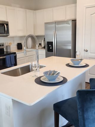 A modern kitchen with sleek white cabinetry, stainless steel appliances, and a chic island set for dining.