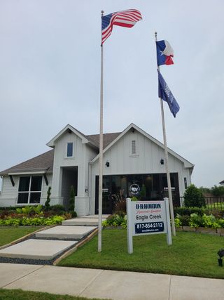 Model Home A charming white home with lush landscaping at Eagle Creek by D.R. Horton in Denton, TX.
