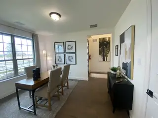 A sophisticated office with a rustic wooden table, plush seating, and accent wall.