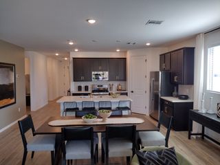 Modern kitchen and dining room with sleek dark cabinets, stainless steel appliances, and stylish decor.