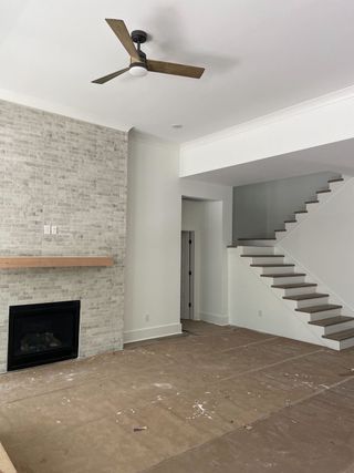 Street view A modern living room featuring a brick accent wall, sleek fireplace, wooden mantel, and a ceiling fan.