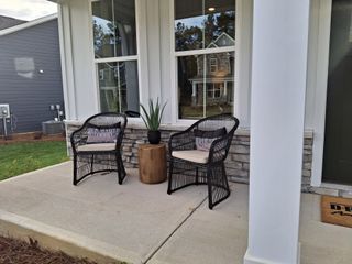 Street view A cozy front porch with wicker chairs, a small table, and a decorative plant, perfect for relaxation.