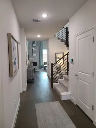 A modern hallway with elegant wood flooring, stylish artwork, and a staircase with sleek railing for a contemporary feel.