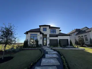 Street view A modern stone facade home with lush landscaping in Santa Rita Ranch by Perry Homes (Liberty Hill, TX).