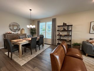 An open-concept living space with a wooden dining table set, a leather couch, and a decorative mirror, flowing into a comfortable living area.
