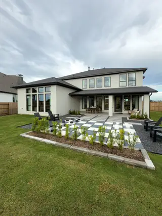 Street view A modern home with expansive windows and a stylish checkerboard patio in Grange 60' by Perry Homes (Katy, TX).
