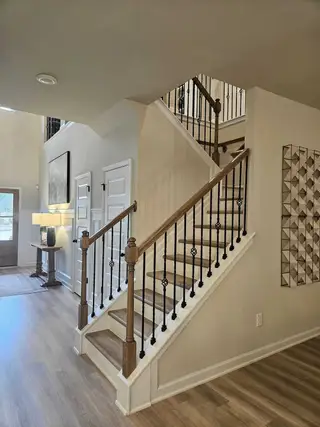 Model Home A grand staircase with iron balusters and wood flooring in Kingston by DRB Homes (Locust Grove, GA).