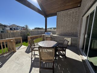 Street view A cozy patio with a round table, woven chairs, and a built-in grill under a wooden pergola. Ideal for outdoor relaxation.