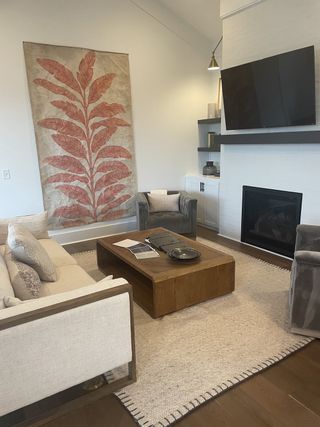 Model Home A cozy living room featuring a large botanical artwork, elegant seating, and a sleek modern fireplace.